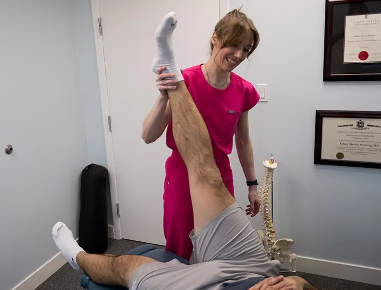 Dr. Kelsey raising the leg of her client when treating sciatica.